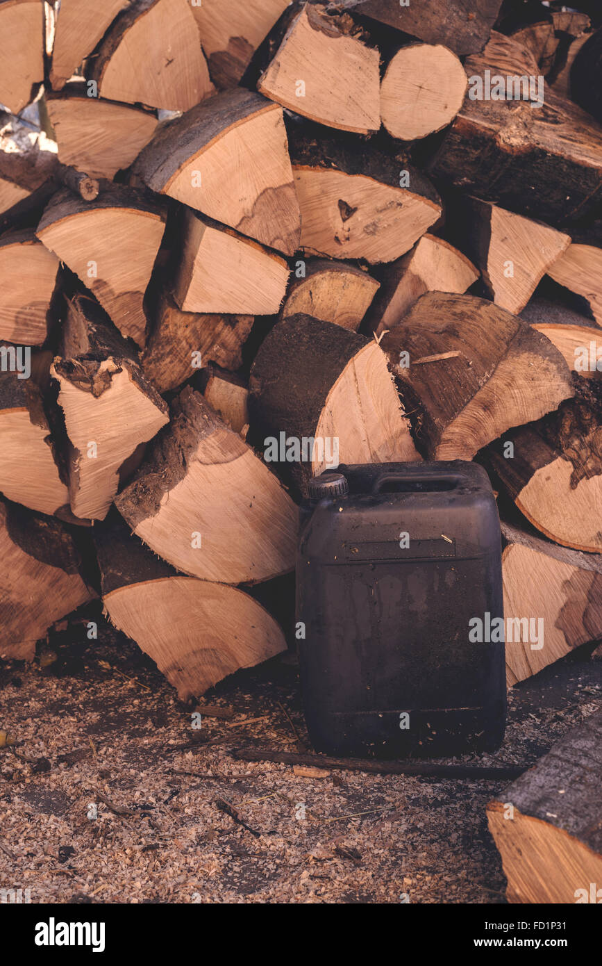 Firewood pile and plastic oil canister for heating season in winter, retro toned image. Stock Photo
