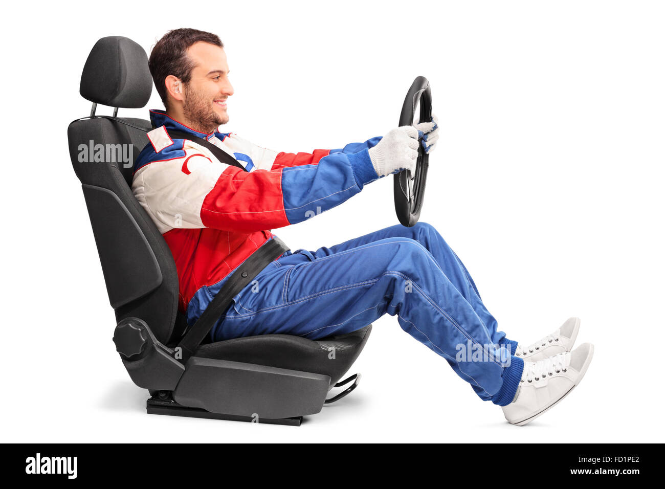 Profile shot of a young car racer holding a steering wheel and pretending to drive isolated on white background Stock Photo