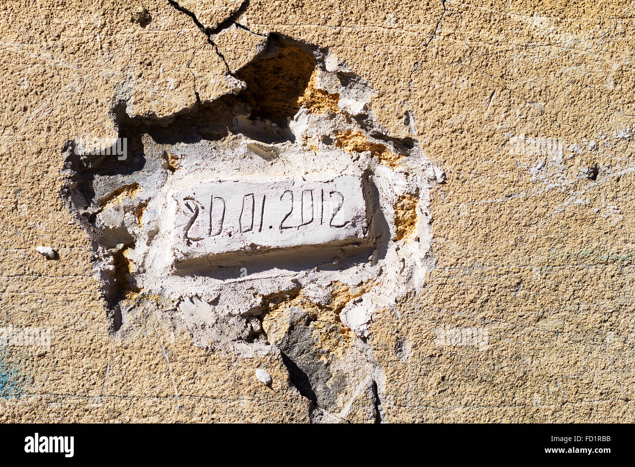 Bricks laid in an old wall with the date of the bookmark. Dirty concrete wall with cracks and scratches. Requires urgent repairs Stock Photo
