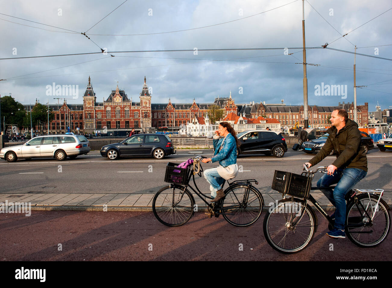 Young People spend with their bikes with the Central Staation to fund another architectural wonder of the Dutch city of Amsterda Stock Photo