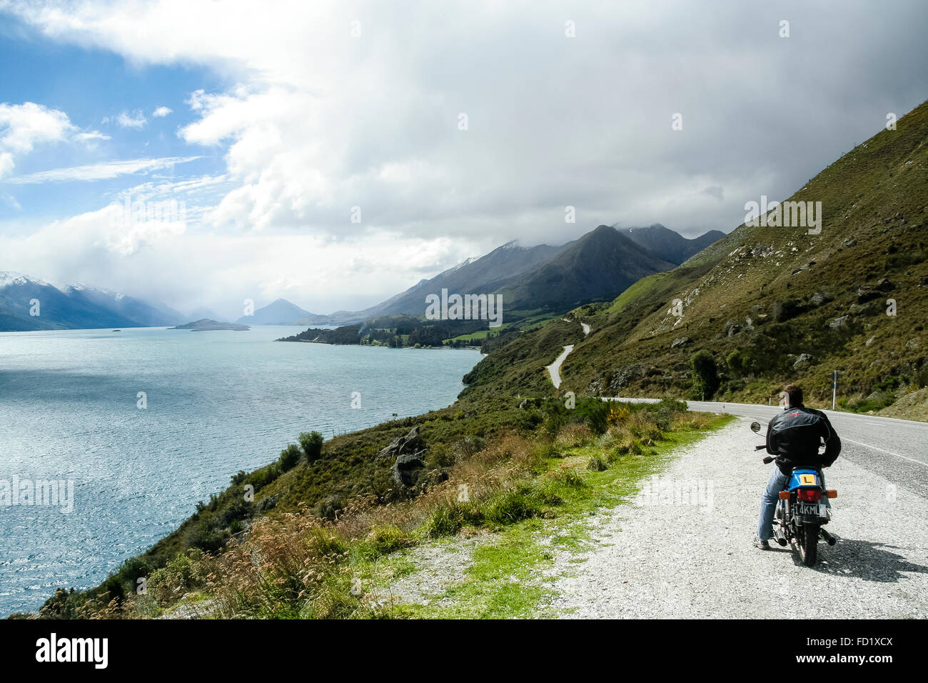 Lake Wakitipu, New Zealand. Motorcycle rider looking at the view on the side of the road. Stock Photo