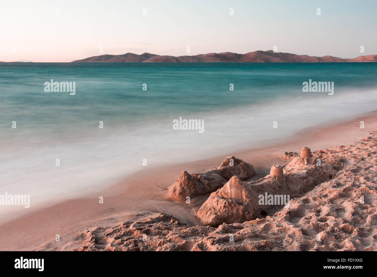 long exposure at dusk on beach with sandcastle in foreground, Pserimos in the background Stock Photo