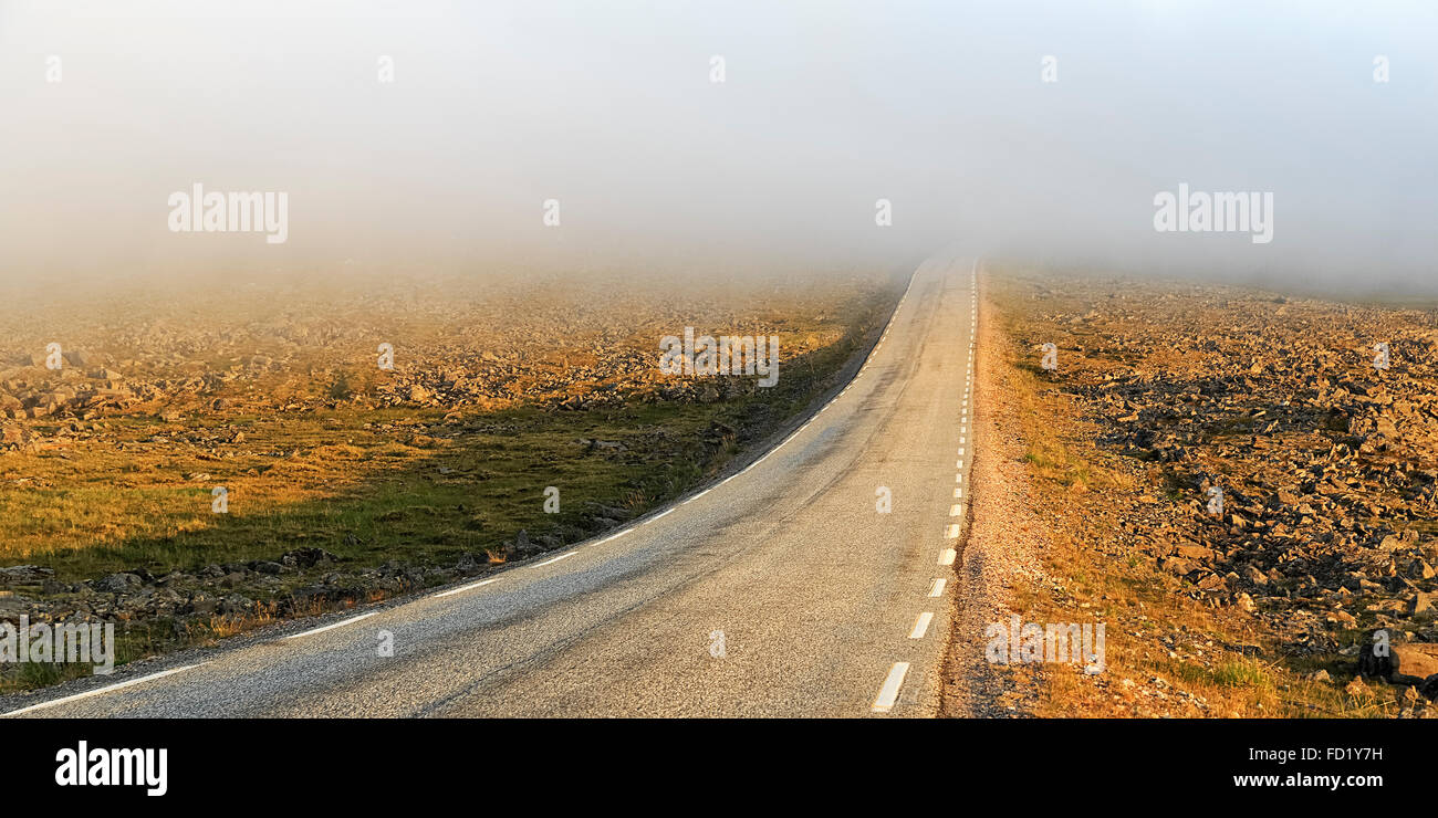 Road through a barren plateau, European route E69, fog, midnight sun, North Cape, Magerøya island, Finnmark County, Norway Stock Photo