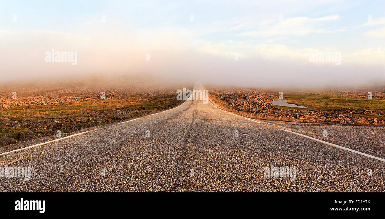 Road through a barren plateau, European route E69, fog, midnight sun, North Cape, Magerøya island, Finnmark County, Norway Stock Photo