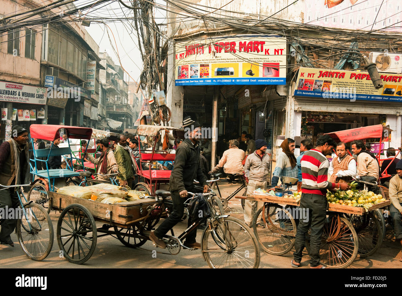 A street scene in Chandni Chowk market, Old Delhi, India with rickshaw and driver and street vendors on a crowded street Stock Photo