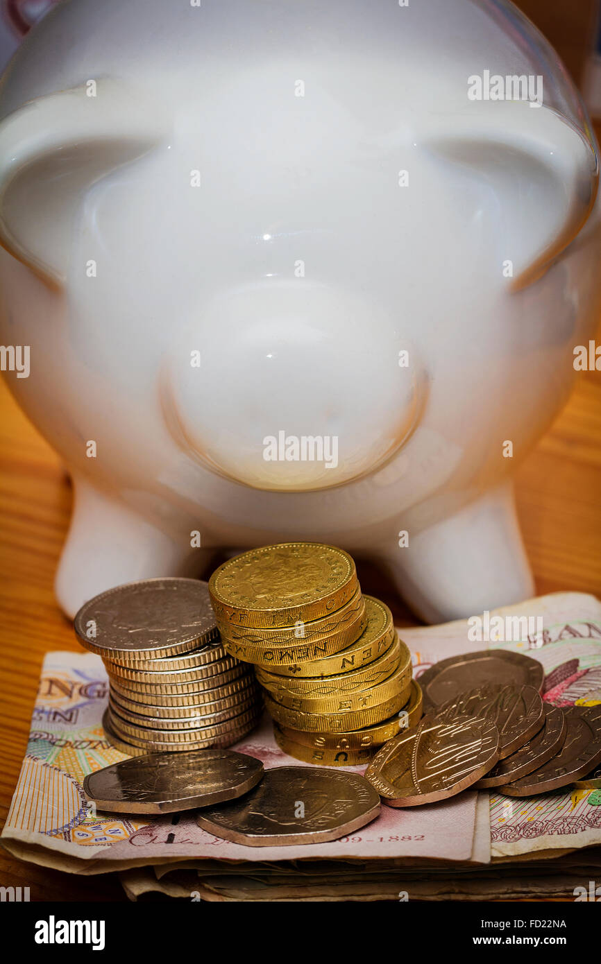 White coloured ceramic piggy bank with bank notes and some GBP coins