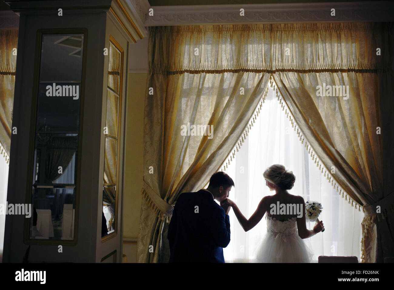 bride and groom standing in front of window Stock Photo - Alamy
