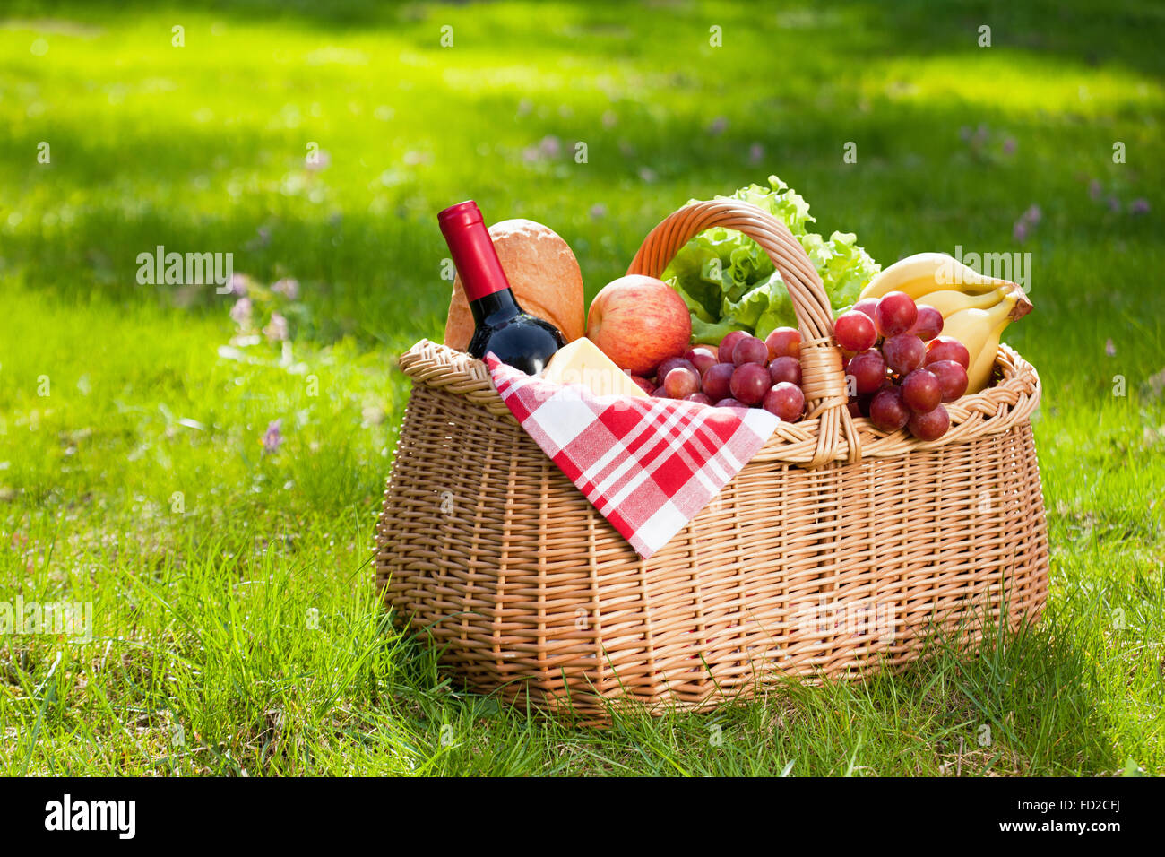 Picnic basket with food on green sunny lawn. Stock Photo