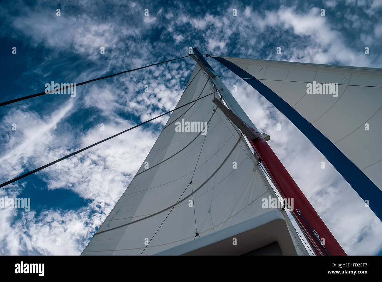 The mast and sails recreational catamaran on a background of cloudy sky ...