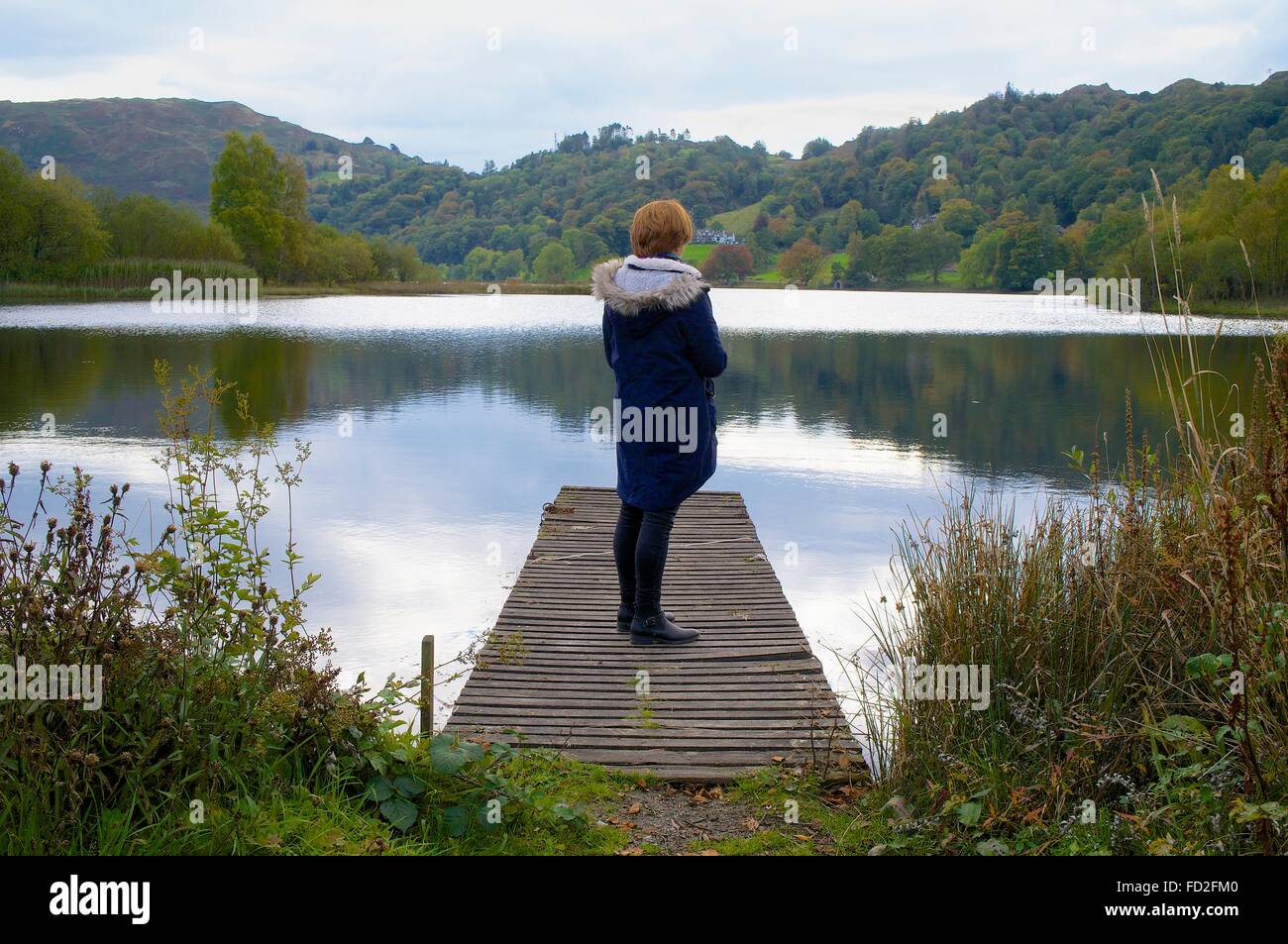 Lake District National Park.  Woman standing on jetty. Grasmere, The Lake District, Cumbria, England, United Kingdom. Stock Photo