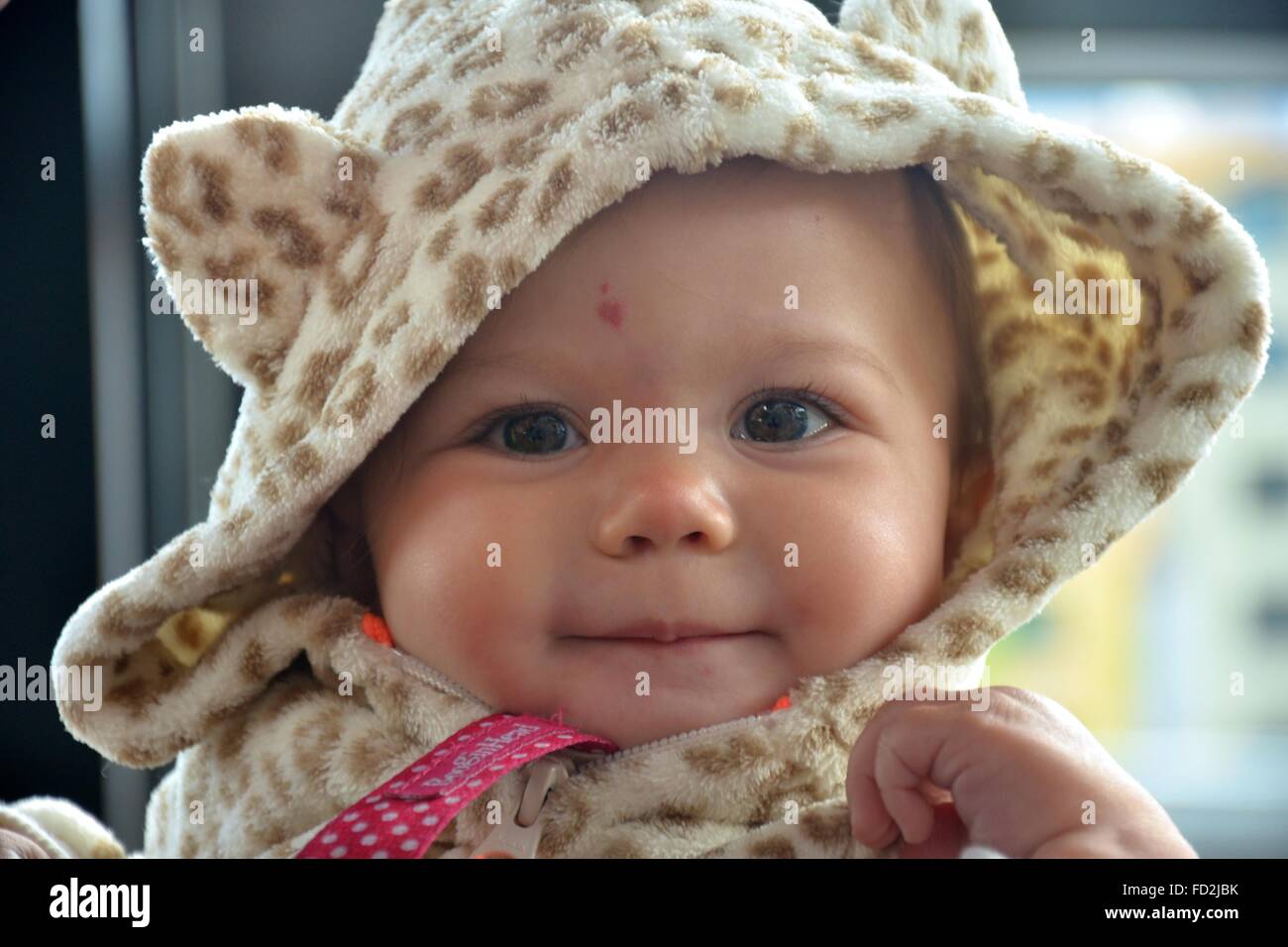 Close up of baby girls face wearing a leopard hoodie. With a heart birth mark on her forehead. Stock Photo