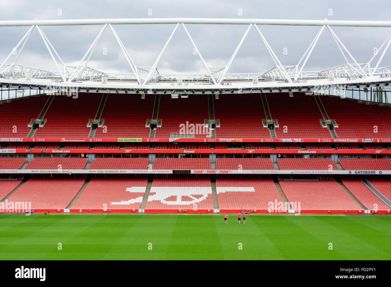 Seats and field inside the Emirates Stadium, home of Arsenal, with the Gunners symbol Stock Photo