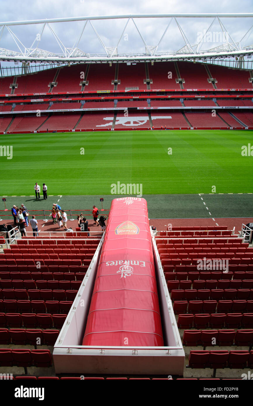 The Arsenal tunnel onto playing pitch in Emirates Stadium, London with seats and Gunners logo Stock Photo