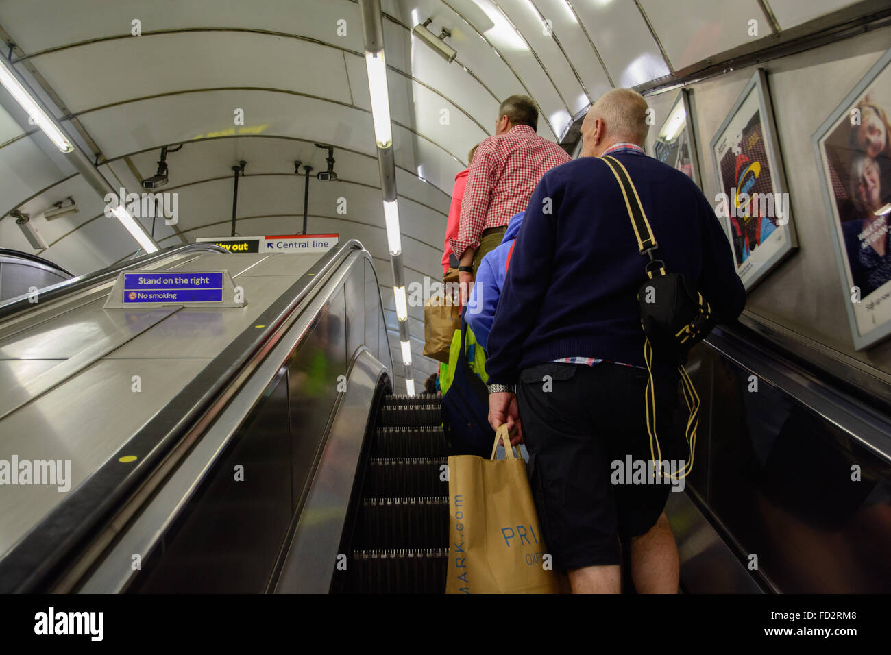 escalator going upstairs with travellers, and a sign with text Stand on the right Stock Photo