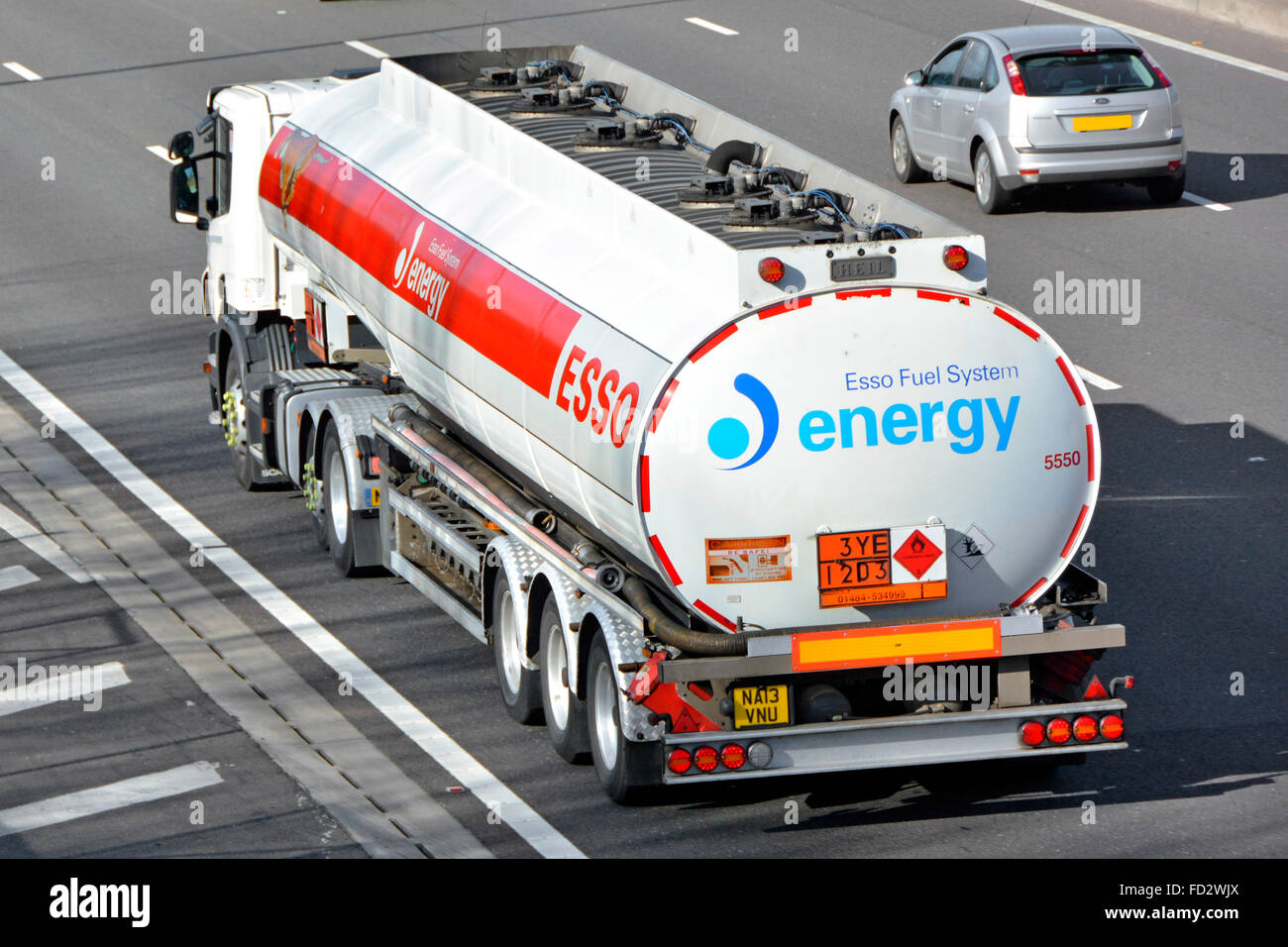 Above side & back view of Esso energy supply chain tanker lorry truck & Hazchem sign rear of articulated petrol trailer transport on M25 motorway UK Stock Photo