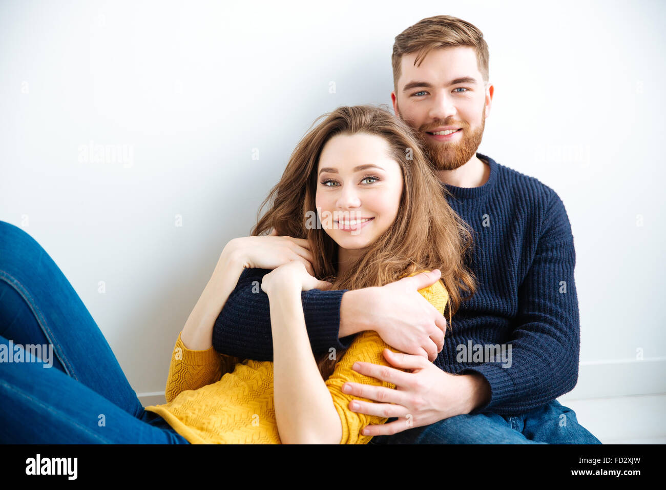 Portrait of a happy young couple hugging and looking at camera over ...