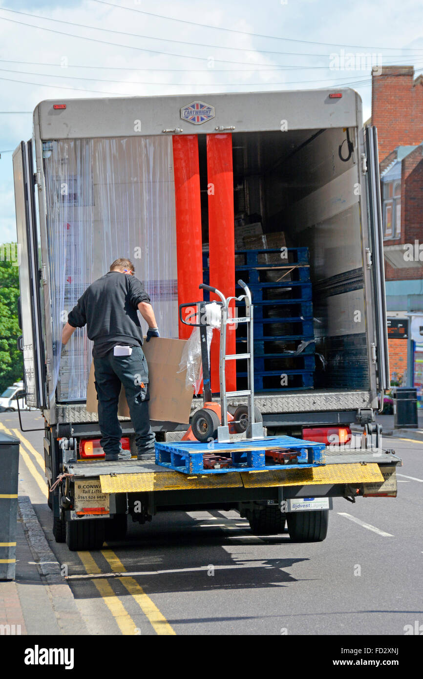 Lorry driver sorting pallet delivery standing on tailgate platform ...