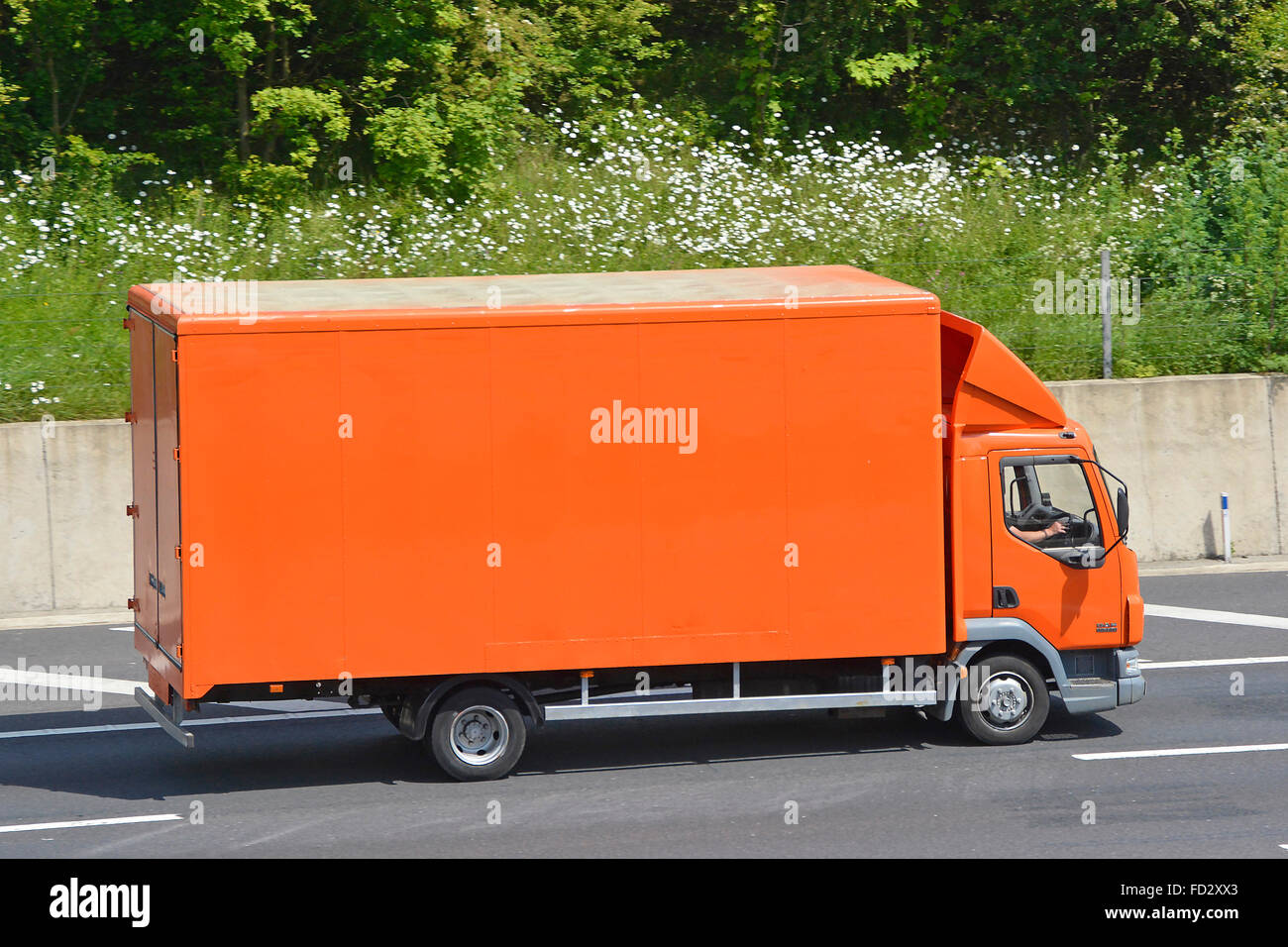 Side view transport via unmarked clean brown colour van lorry truck delivery driver travelling along M25 motorway Essex England UK Stock Photo