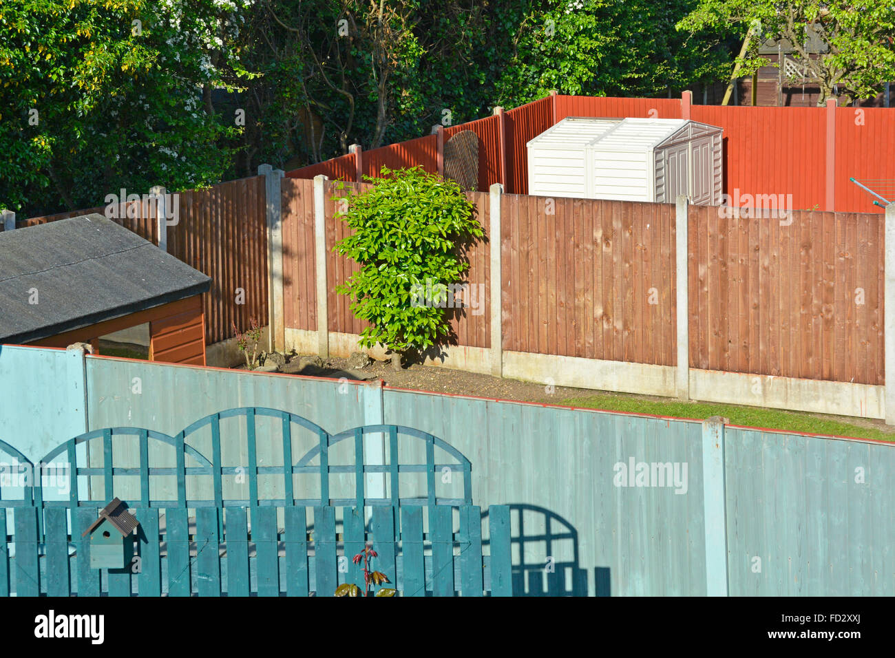 Back garden sheds and panel fence between neighbours with hawthorn hedge beyond Stock Photo