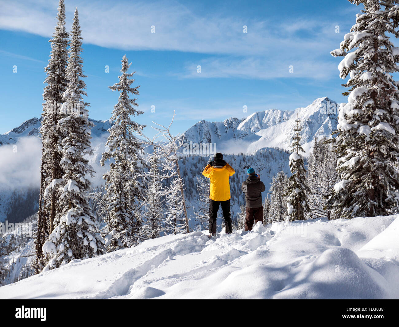 Back country skiers enjoy a winter view of Selkirk Mountains from remote Mount Carlyle Lodge;  British Columbia; Canada Stock Photo