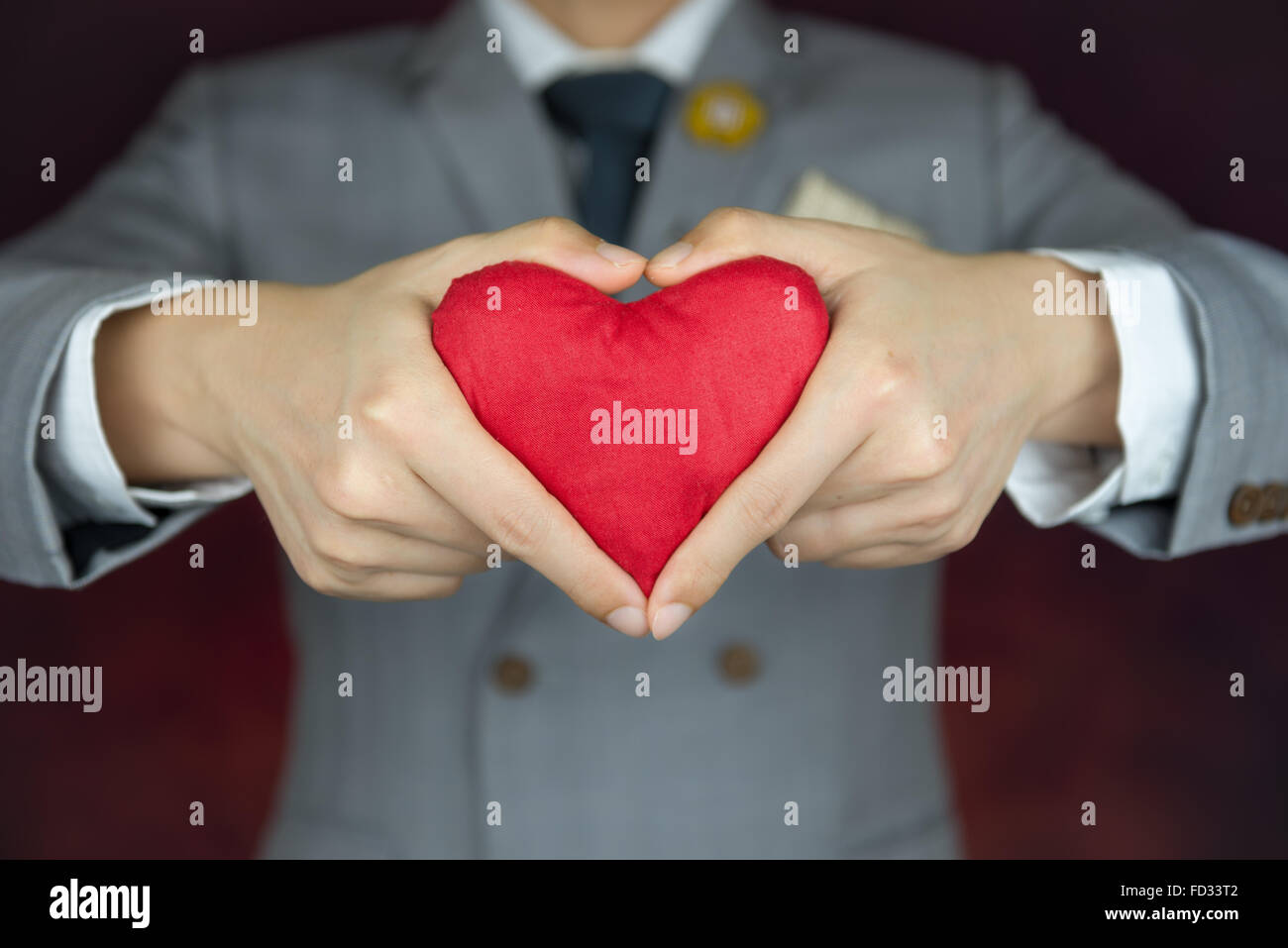 red heart in hands with heart gesture, valentine's concept, man in grey suit Stock Photo