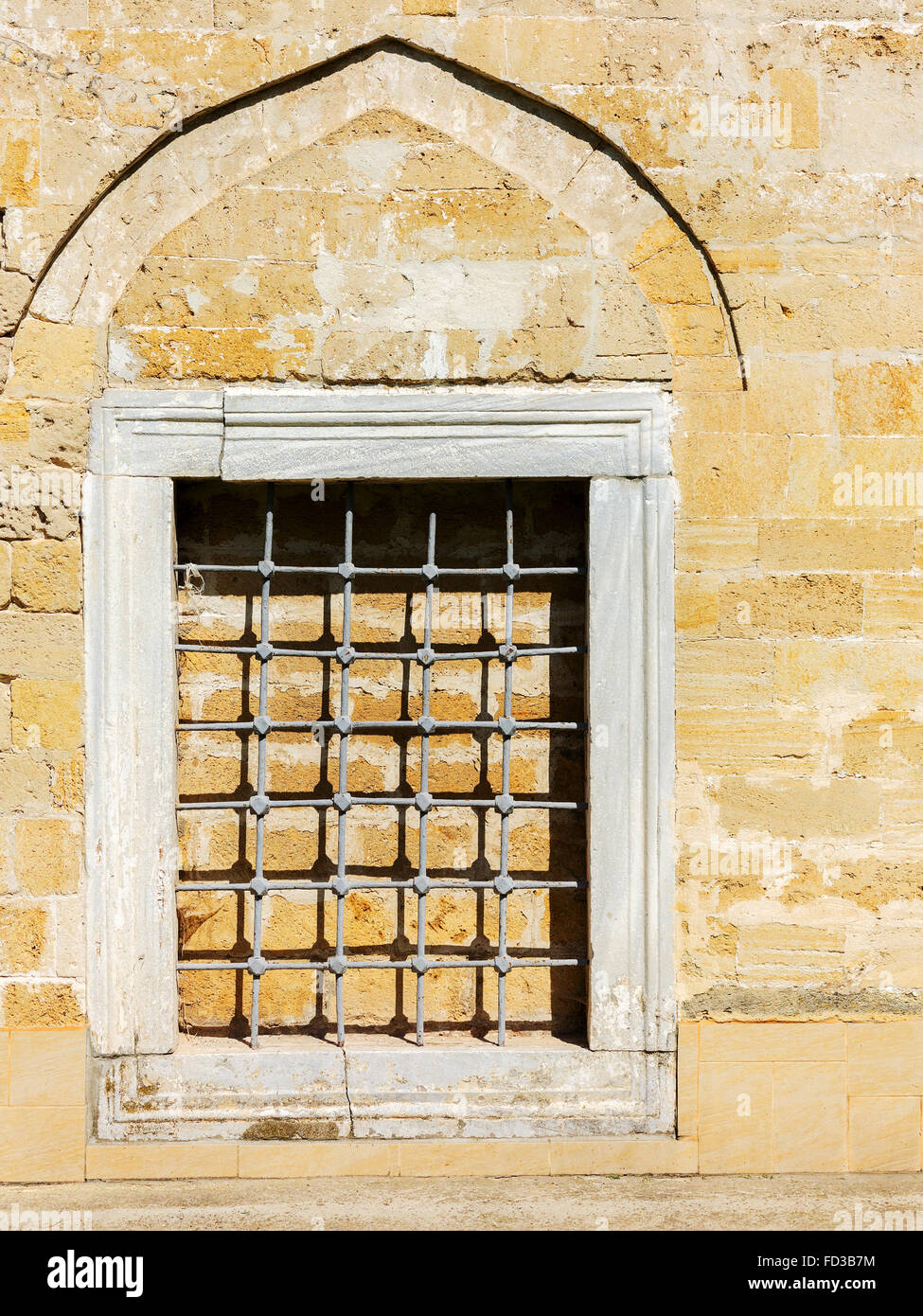 Old window with creative metal bars on the white stone wall Stock Photo ...