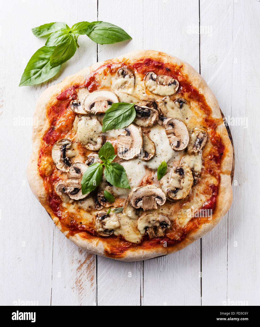 Pizza with mushrooms and basil on white wooden background Stock Photo