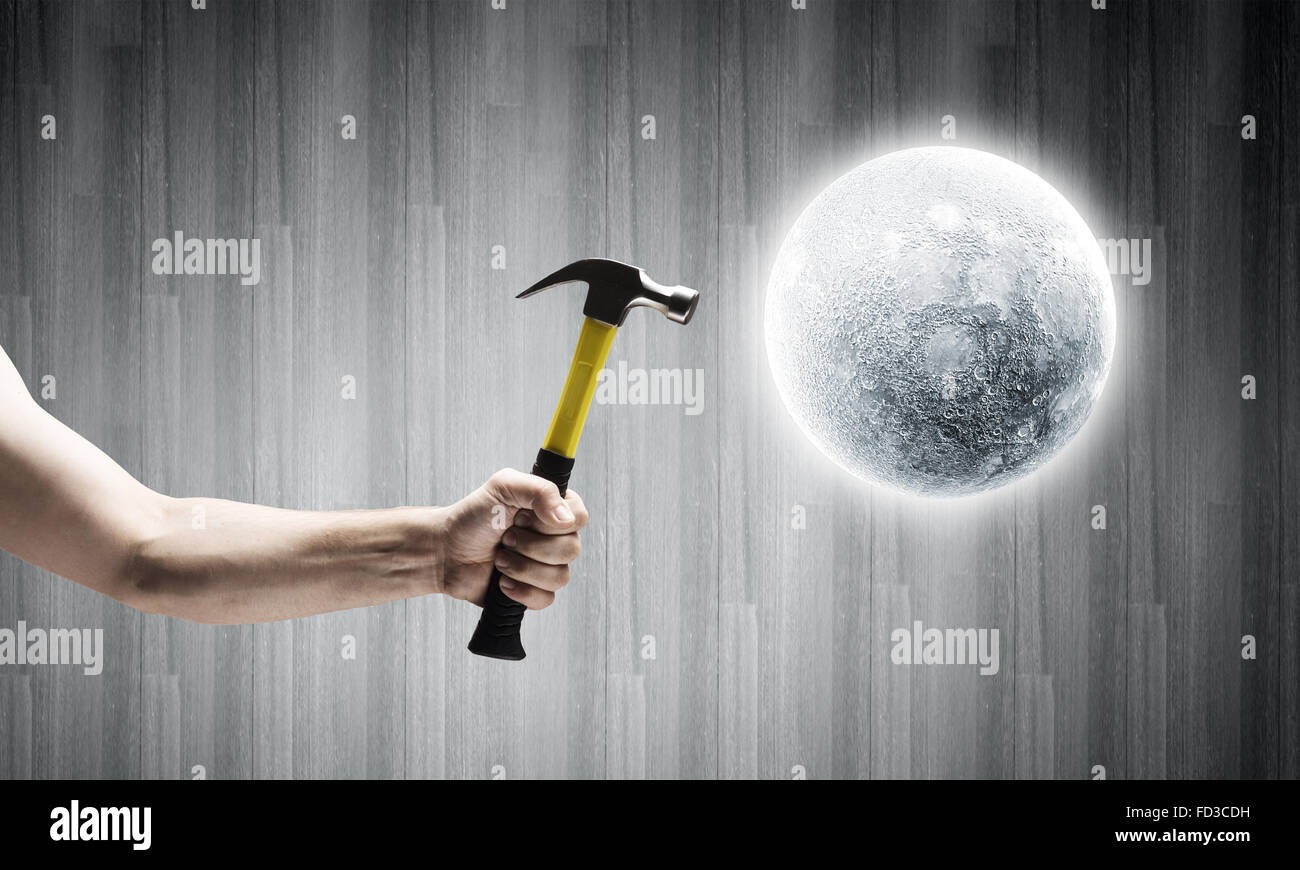 close-up-of-hammer-in-human-hand-hitting-moon-planet-FD3CDH.jpg