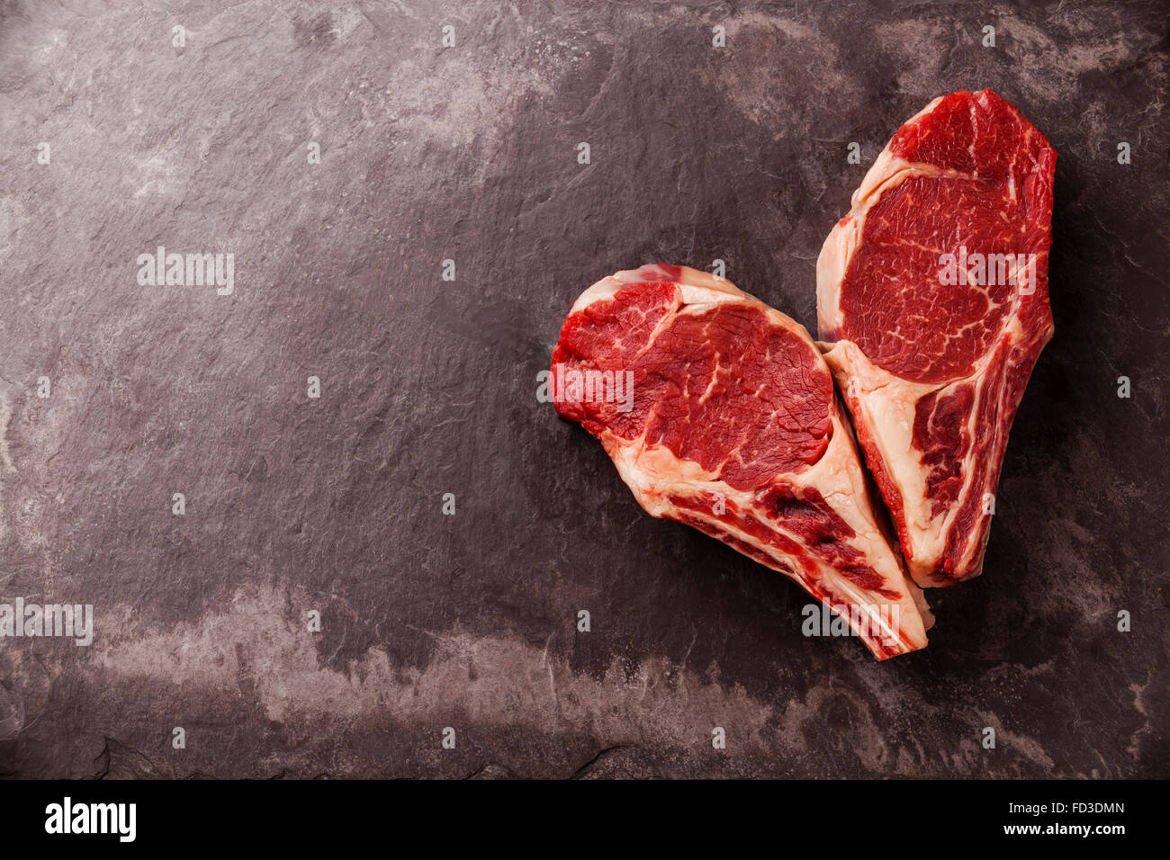 Heart shape Raw fresh meat Ribeye Steak on bone on stone slate