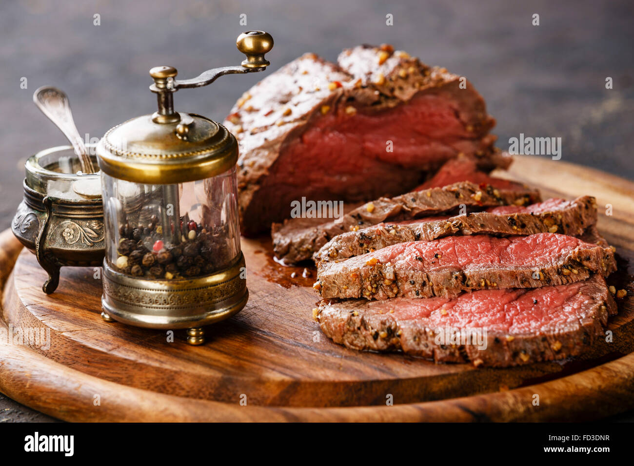 Roast beef on cutting board with saltcellar and pepper mill Stock Photo