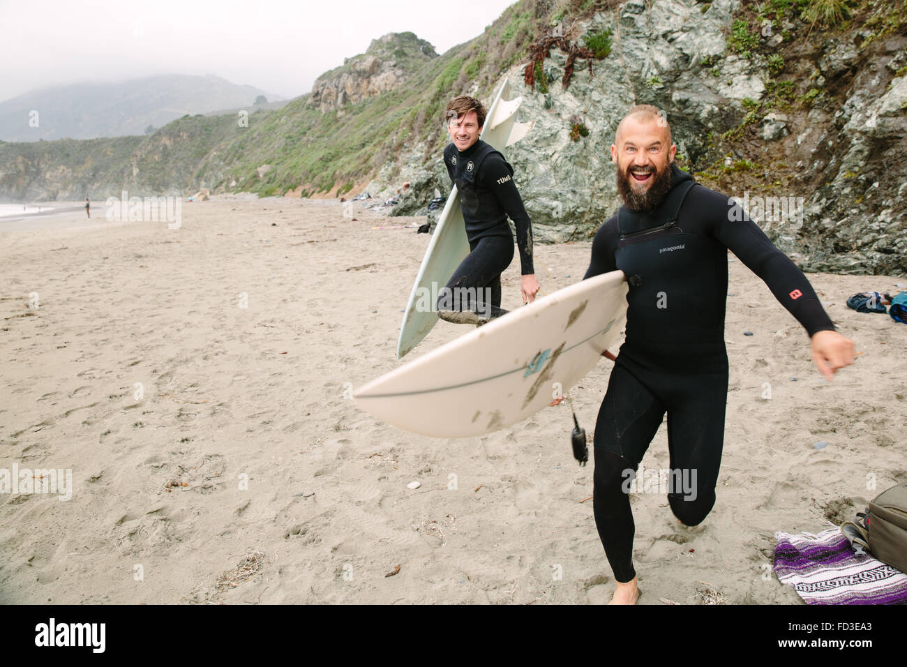Two surfers goof around on the beach before jumping in the water to catch waves in Big Sur, California. Stock Photo