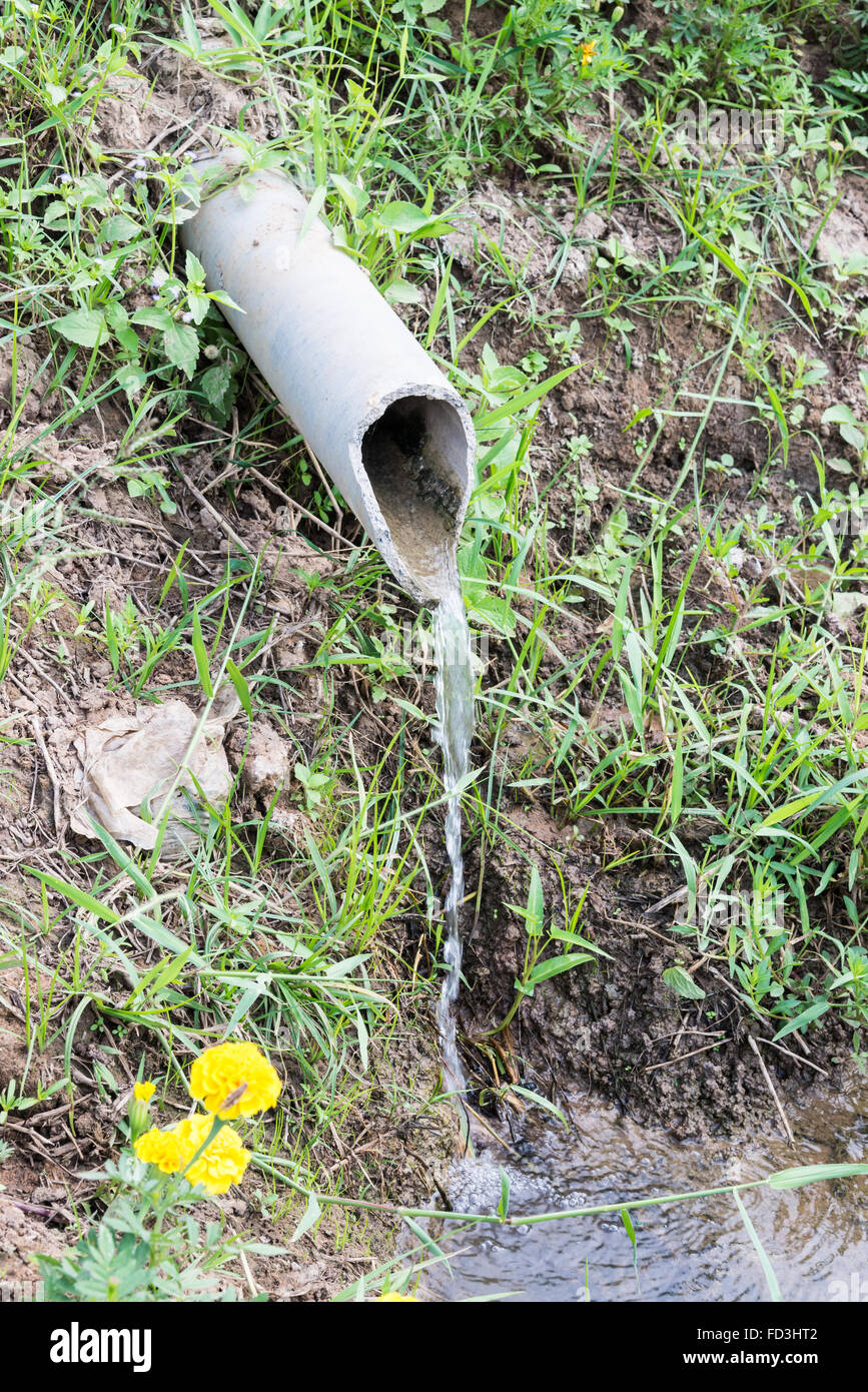 Flowing of pure water from the old pipe in the farmland. Stock Photo