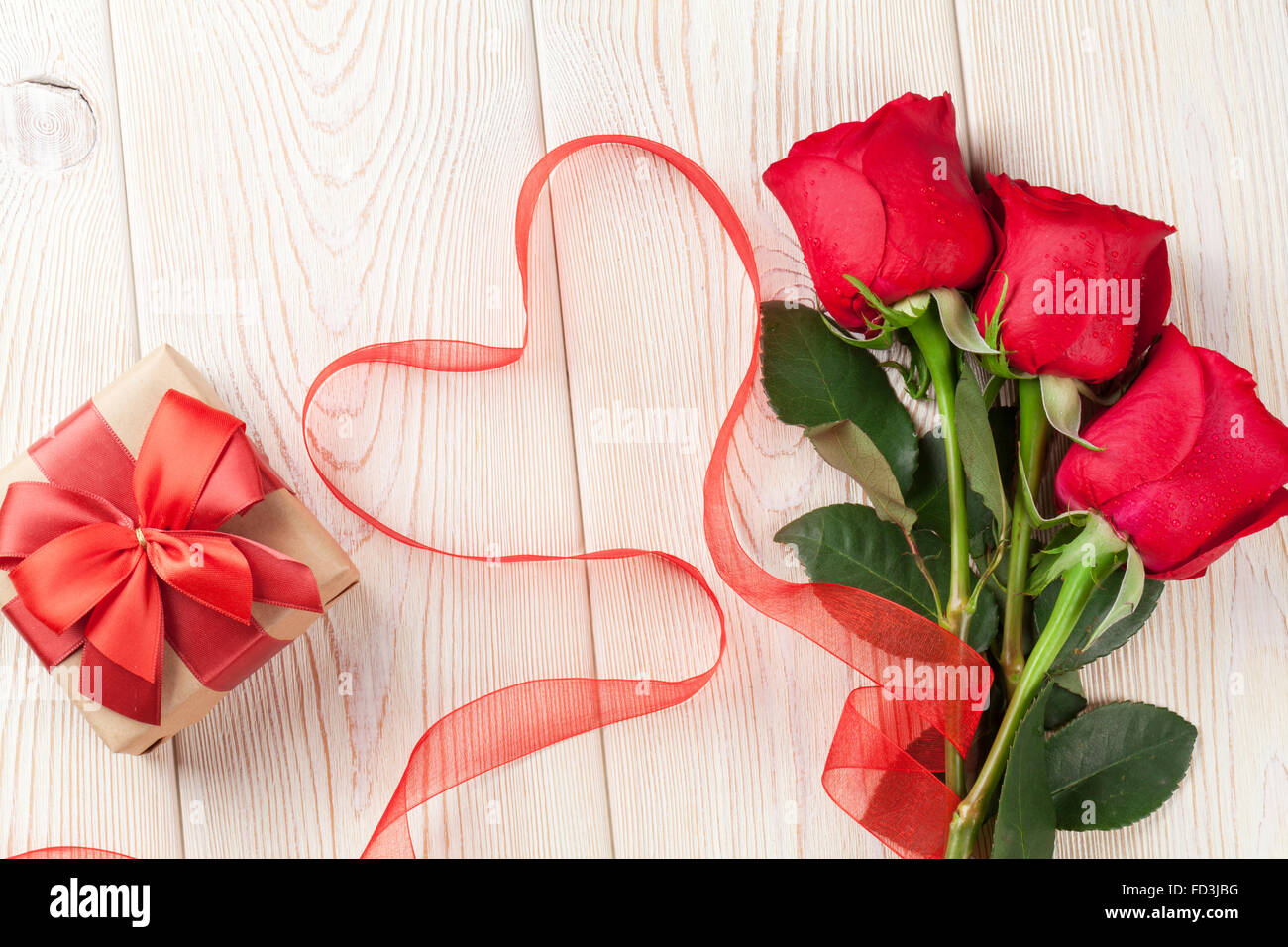 Red roses, Valentines day gift box and heart shaped ribbon over wooden ...