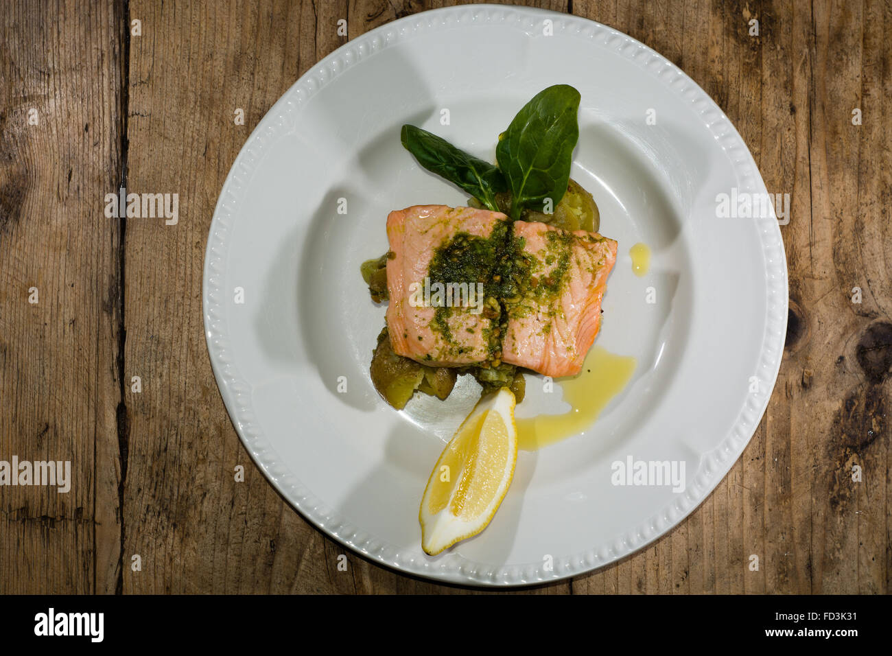 Salmon fillet, pesto and crushed potato plate from above. A restaurant prepared fish dish presented on a white plate Stock Photo
