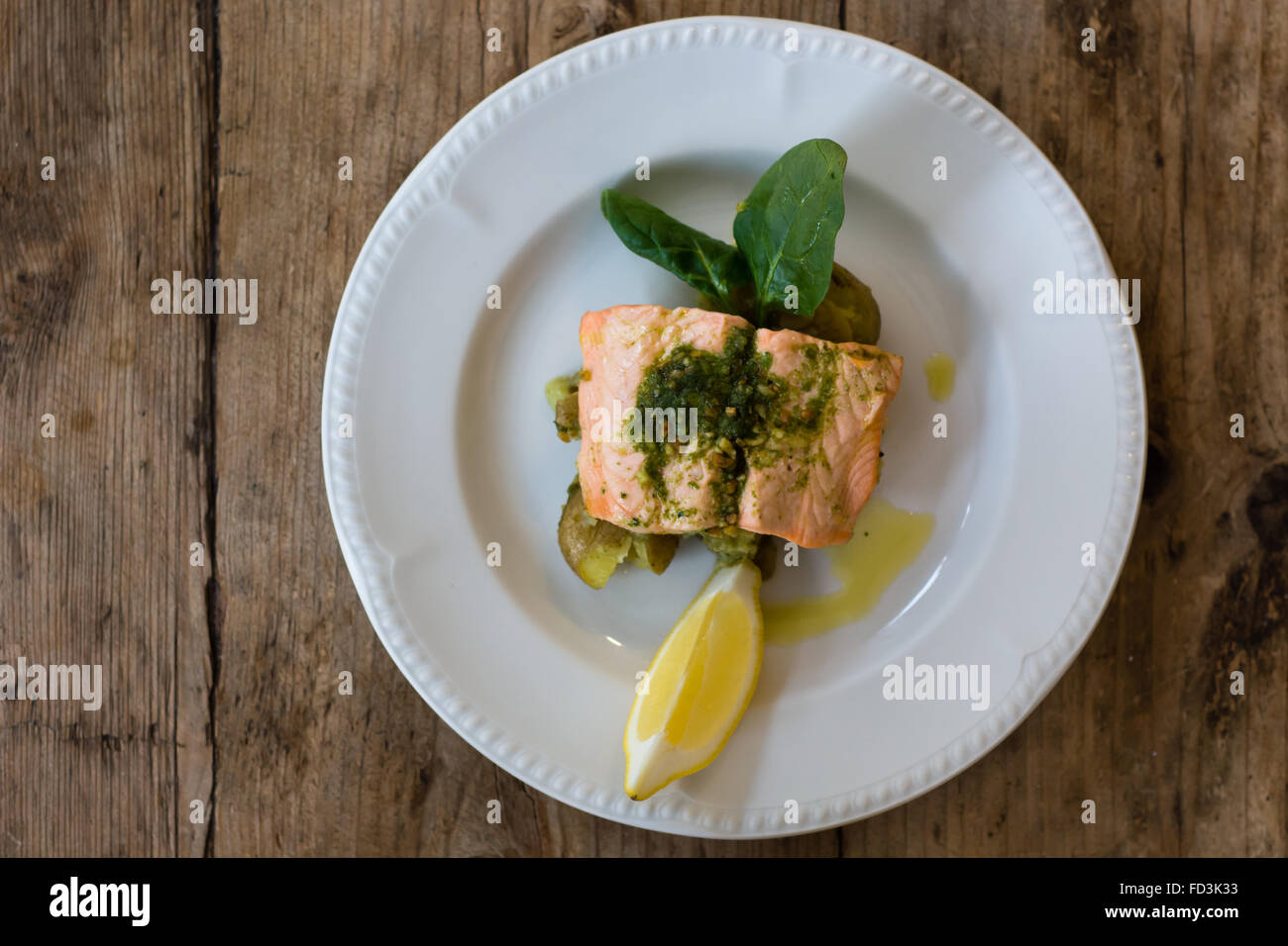 Salmon fillet, pesto and crushed potato plate from above. A restaurant prepared fish dish presented on a white plate Stock Photo