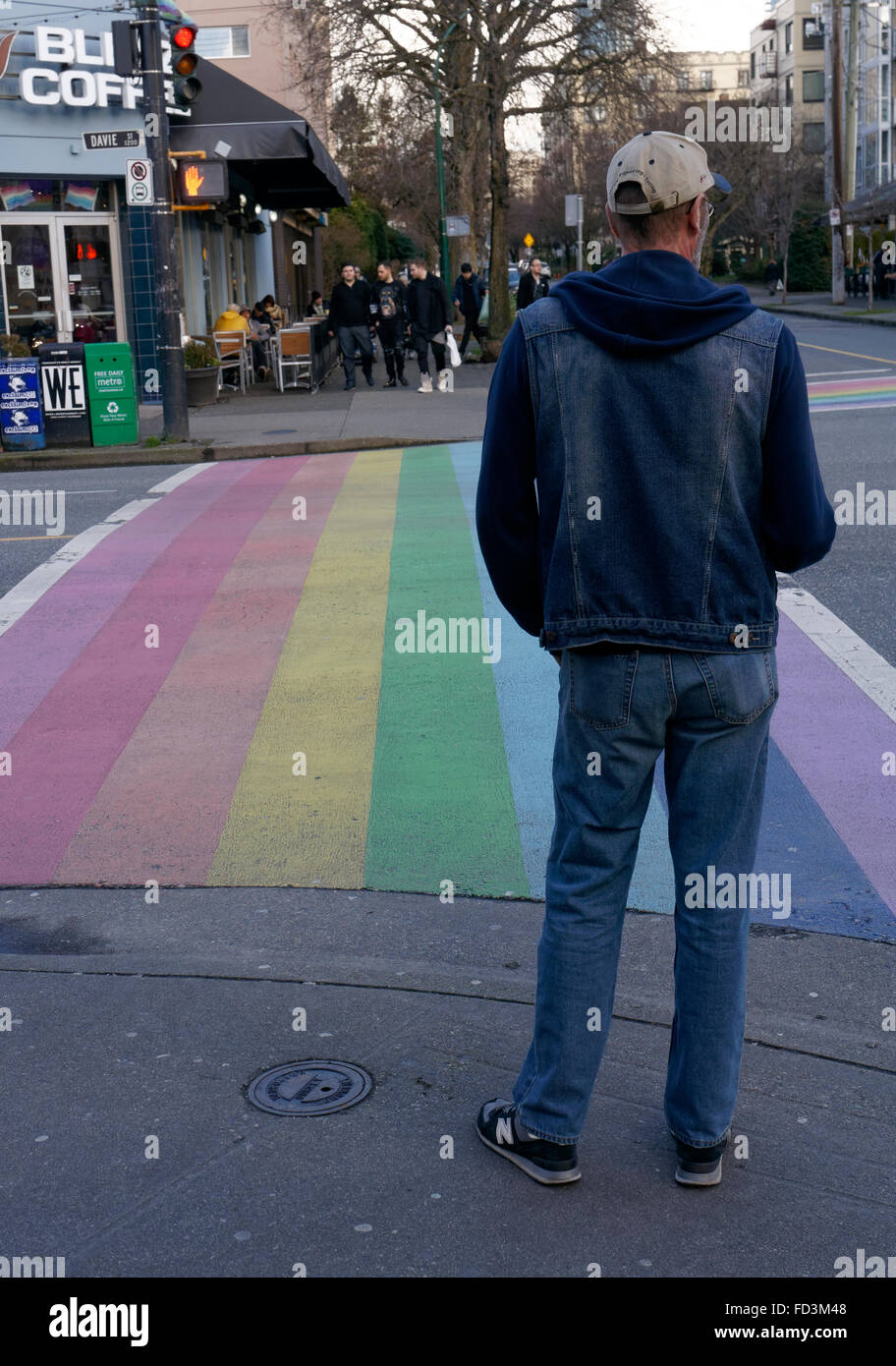 Man waiting to use the rainbow crosswalk symbolic of gay pride in the