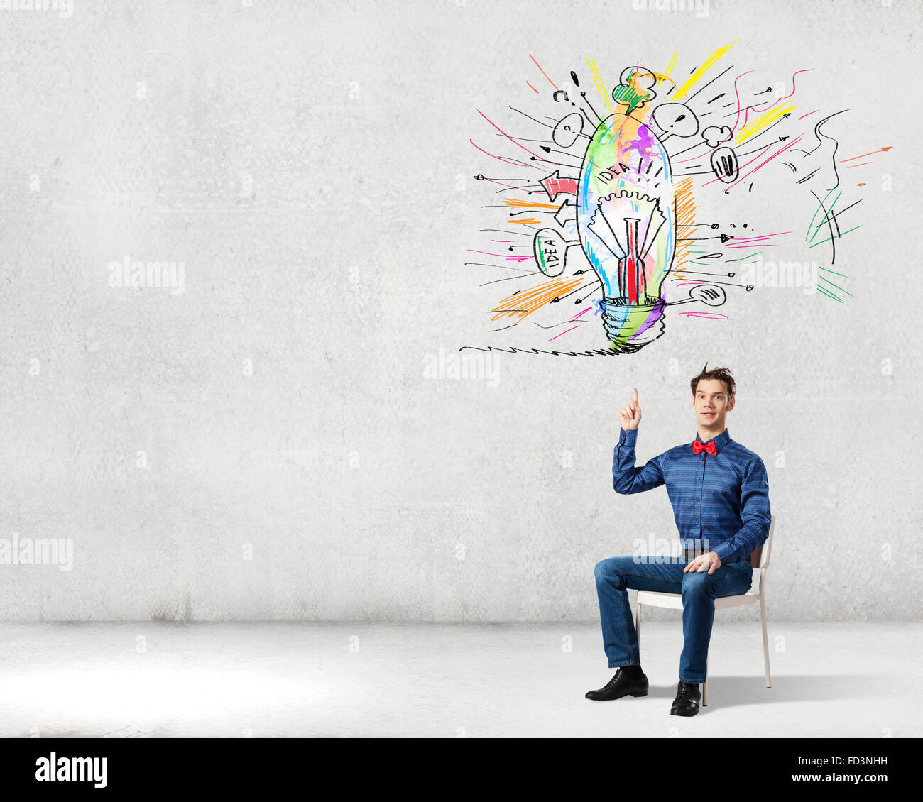 Young funny guy sitting in chair and pointing upwards Stock Photo Alamy