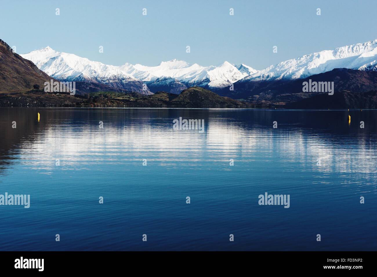 Beautiful sunny day reflection on the blue Lake Wanaka with snowy mountains in the background. Stock Photo