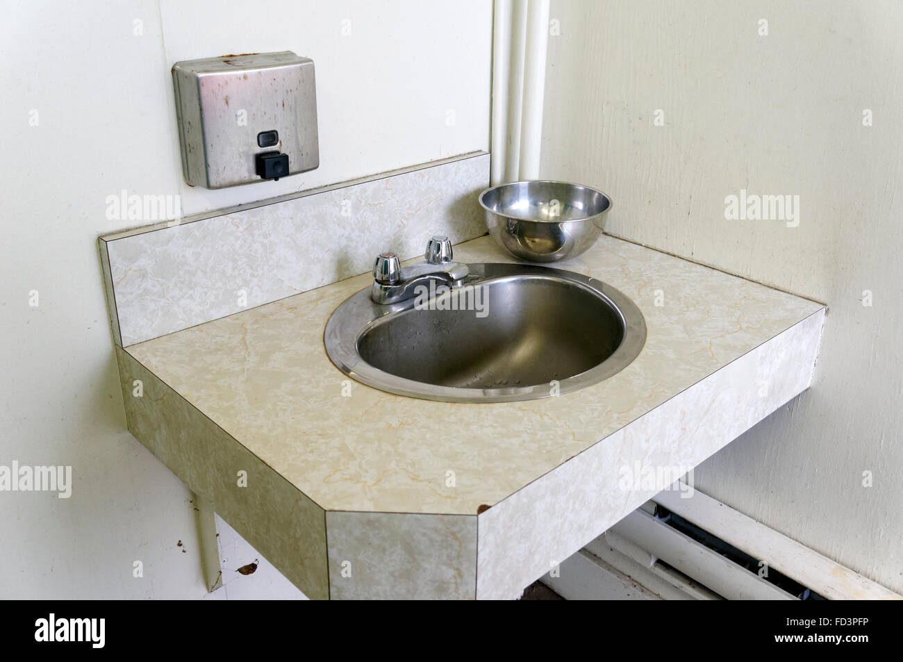 Stainless steel washbasin and soap dispenser in a public washroom Stock Photo