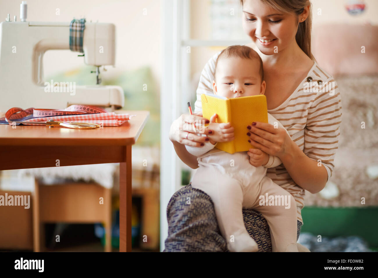 Mother and baby reading a book together at home. Stock Photo