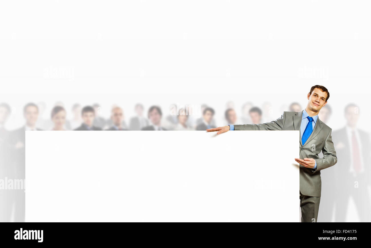 Image of young man holding blank banner with crowd of business people ...
