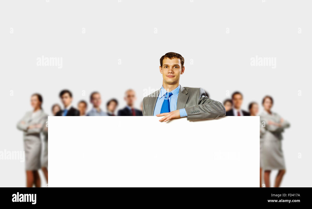 Image of young man holding blank banner with crowd of business people ...