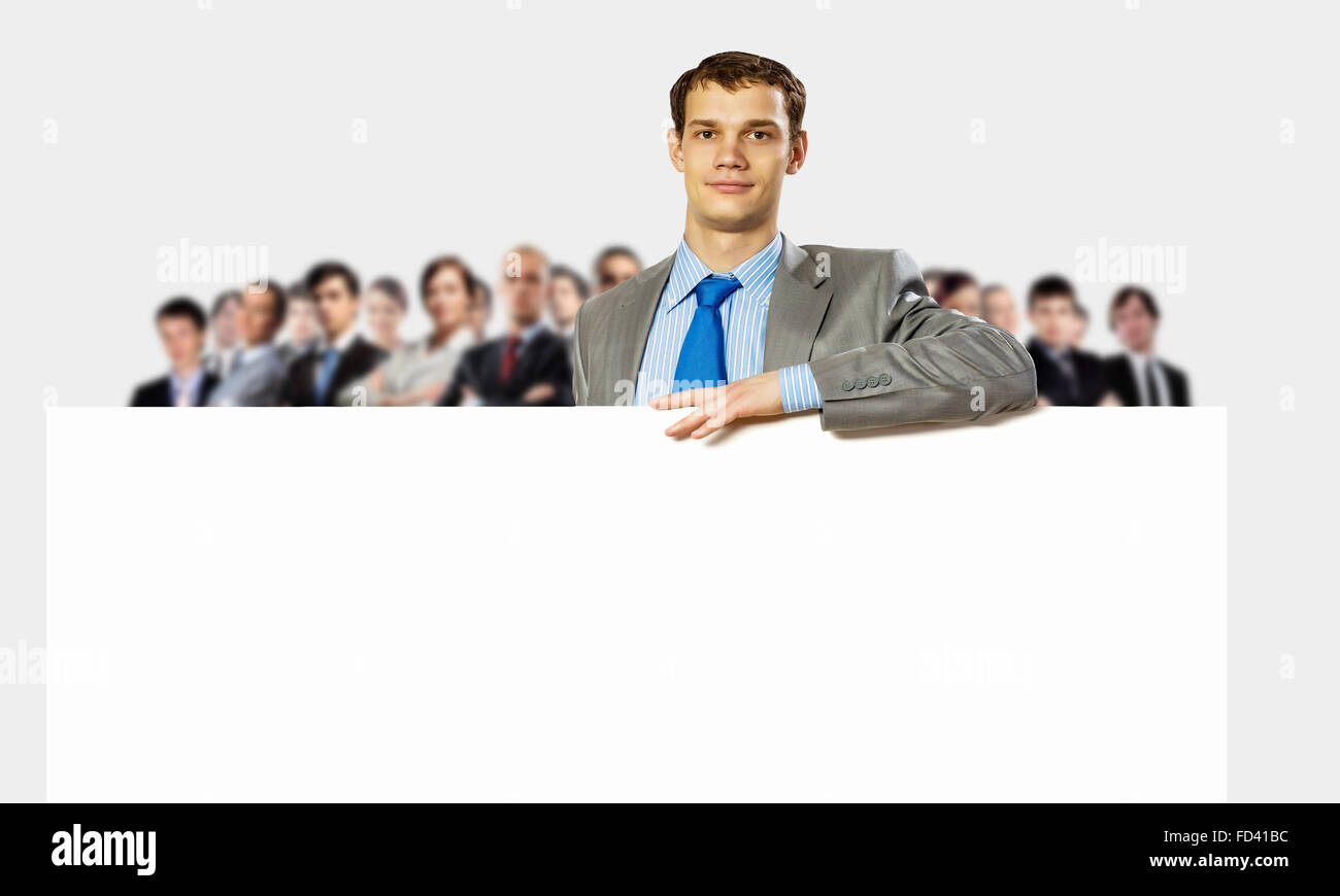 Image of young man holding blank banner with crowd of business people ...