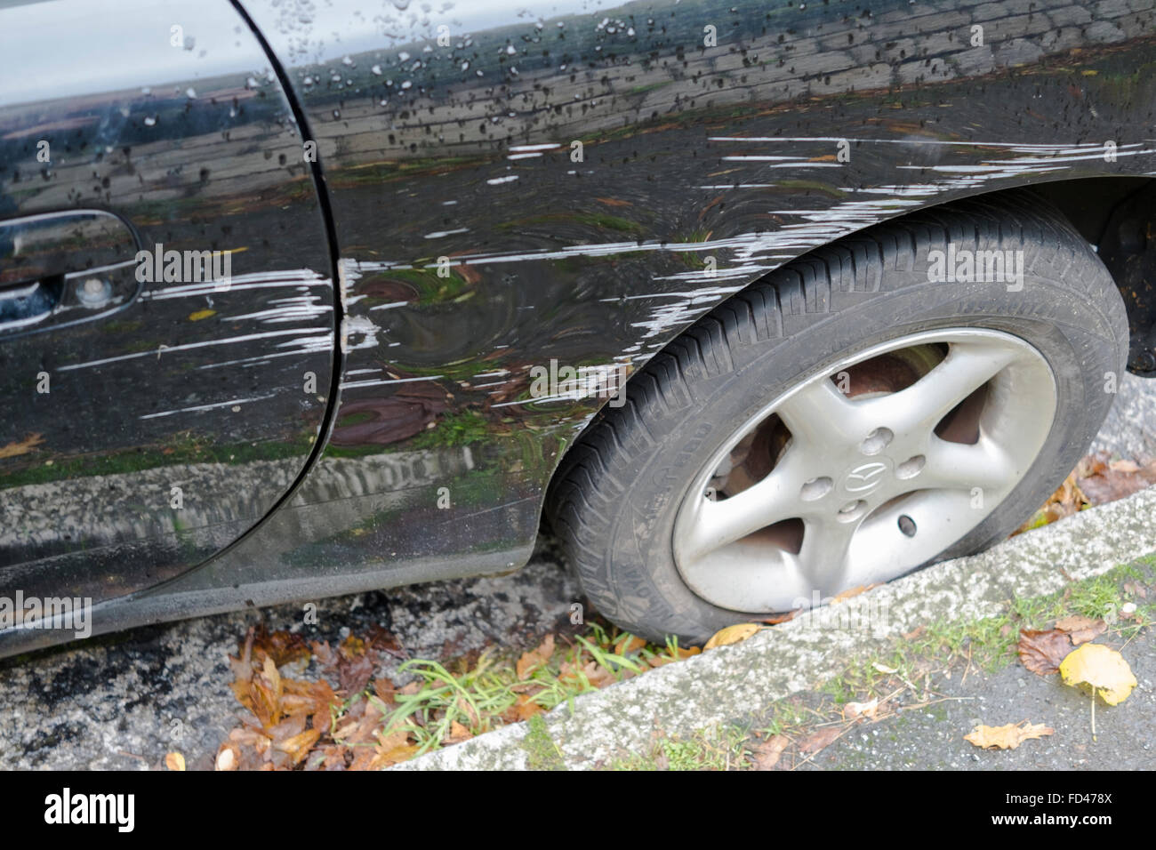 The damaged side of a black car that has been involved in a scrape