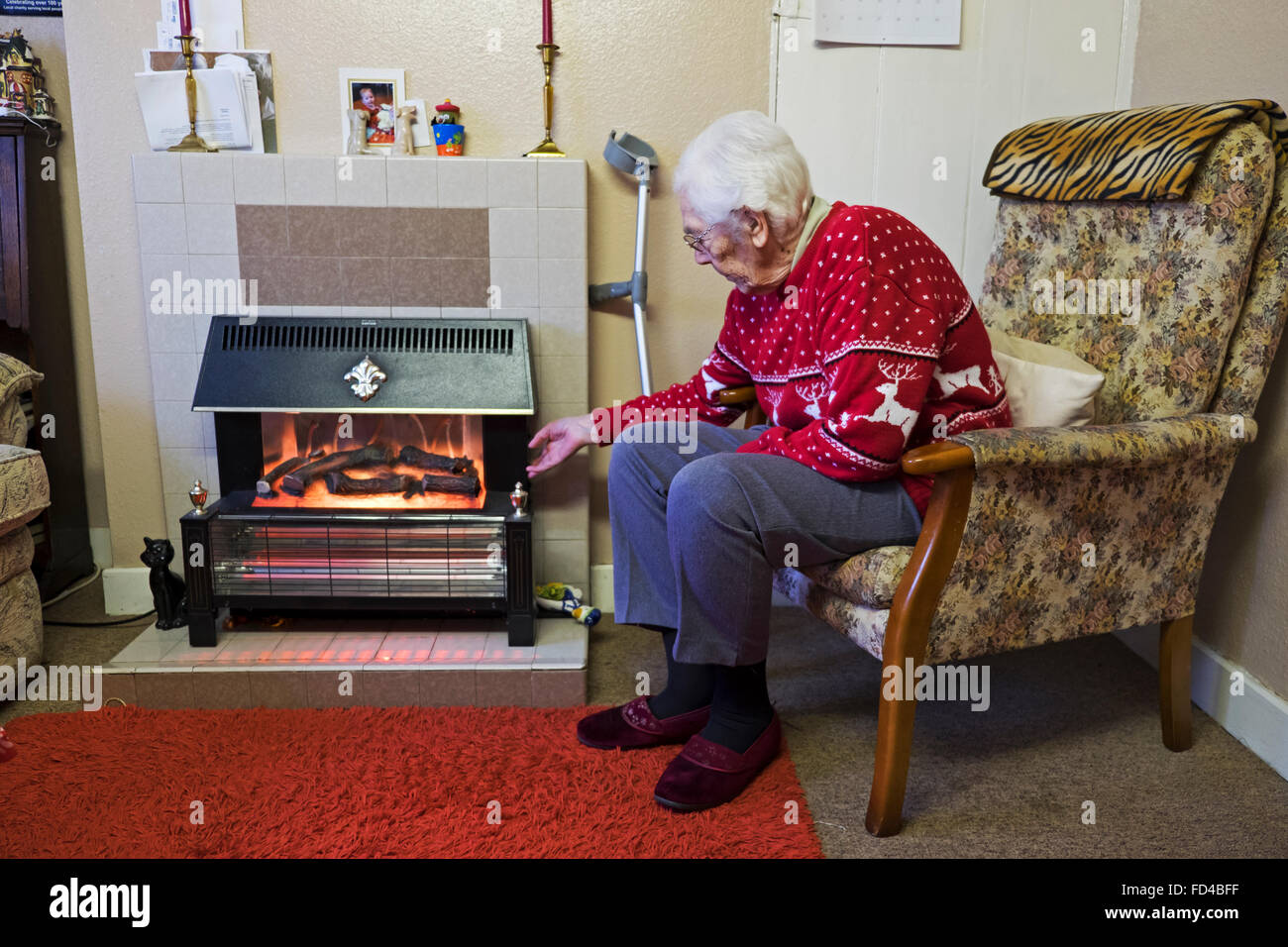 Old age pensioner turning up the heat on an electric fire Stock Photo