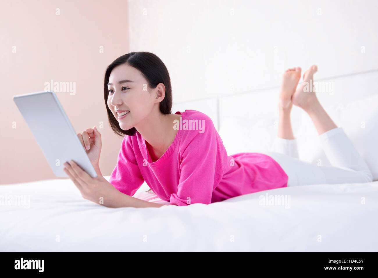 Young woman using digital tablet in bed Stock Photo