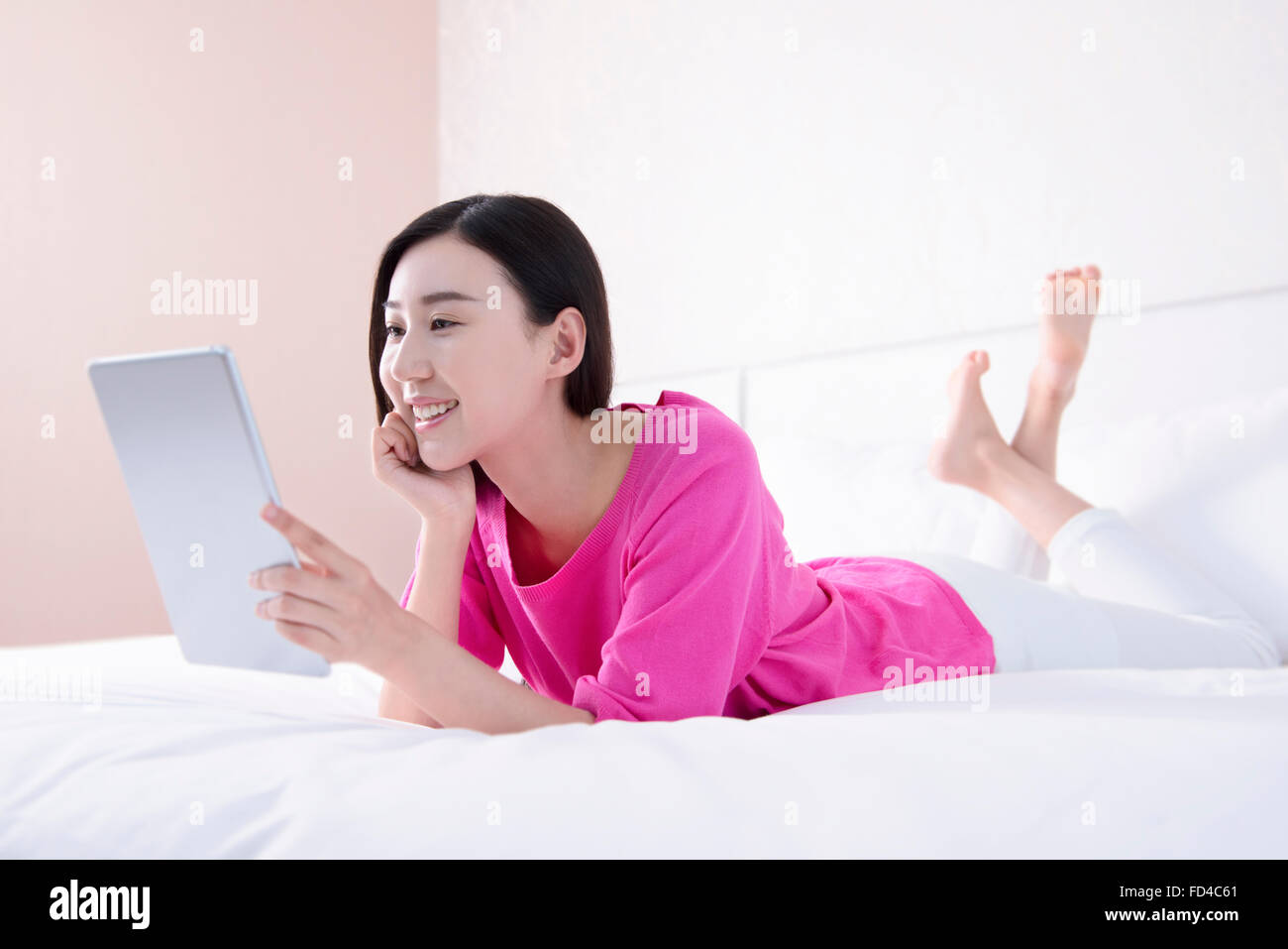 Young woman using digital tablet in bed Stock Photo