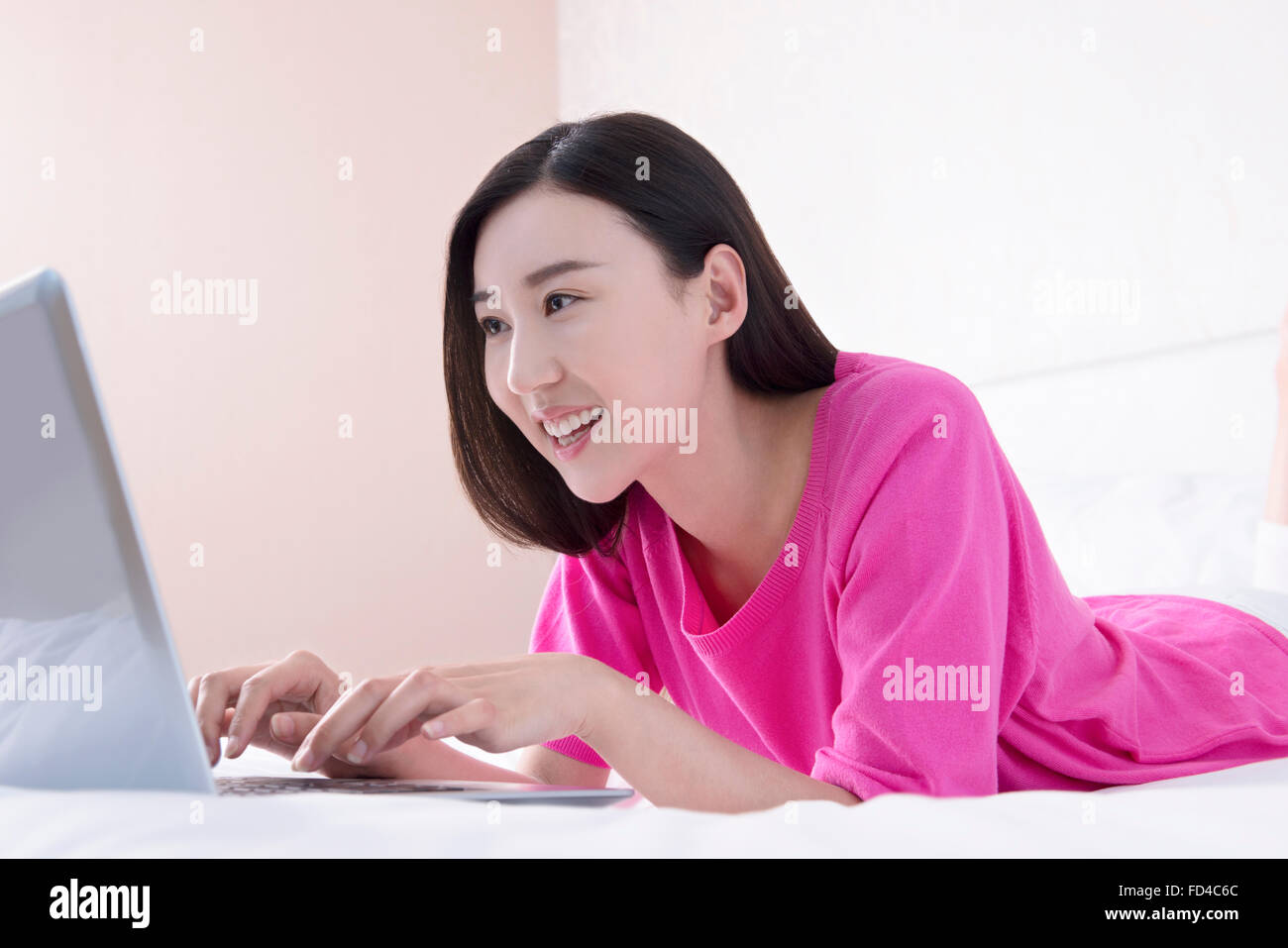 Young woman using laptop in bed Stock Photo