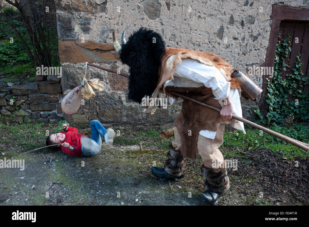 Los zamarrones persiguen a los niños con unos palos con vegigas hinchadas por las calles del pueblo, durante la mascarada Stock Photo