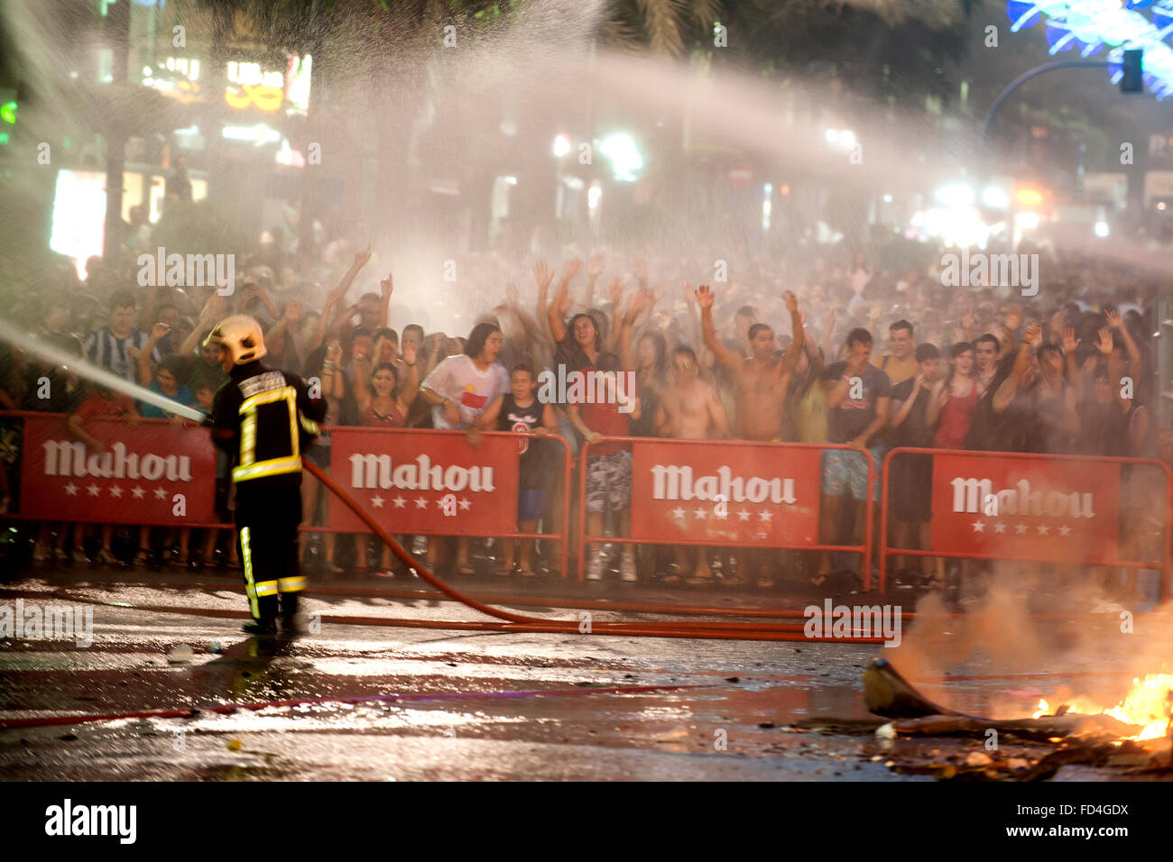 Firefighters wet the public attending the cremá night of bonfires. Stock Photo